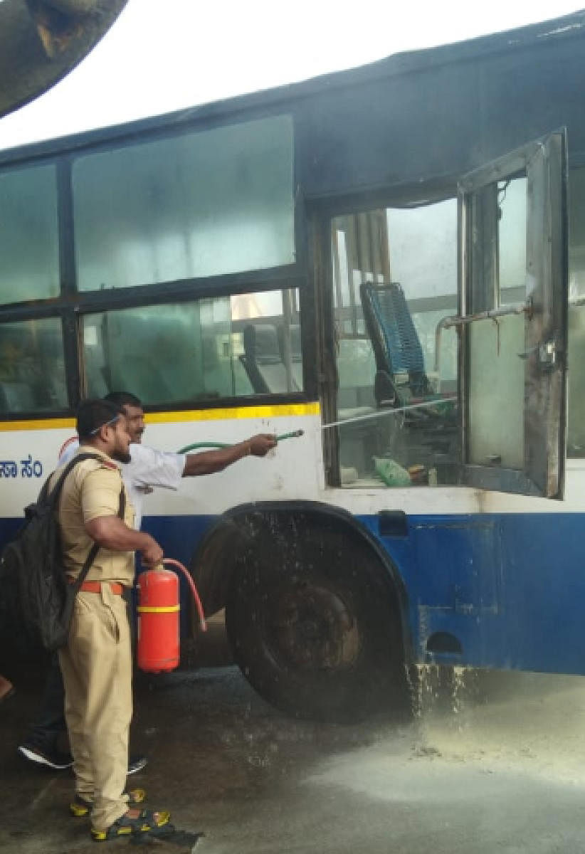Fire personnal put off the fire and smoke from inside the BMTC bus which got fire due to short circuit near Bengaluru International Exhibition Center at Madapura in Bengaluru on Monday.