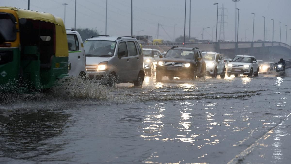 Traffic move on a water logged street during rains in New Delhi, Tuesday morning. PTI Photo 