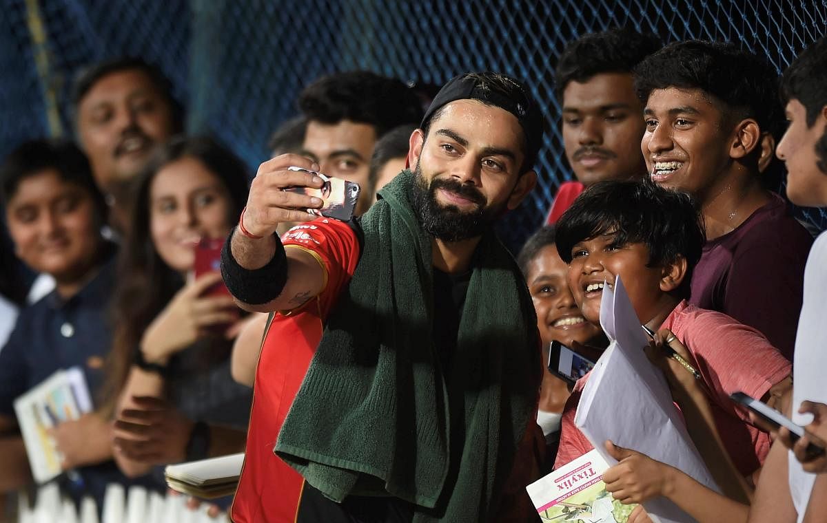 Royal Challengers Bangalore skipper Virat Kohli takes a selfie with fans at the M A Chidambaram Stadium ahead of the IPL. PTI