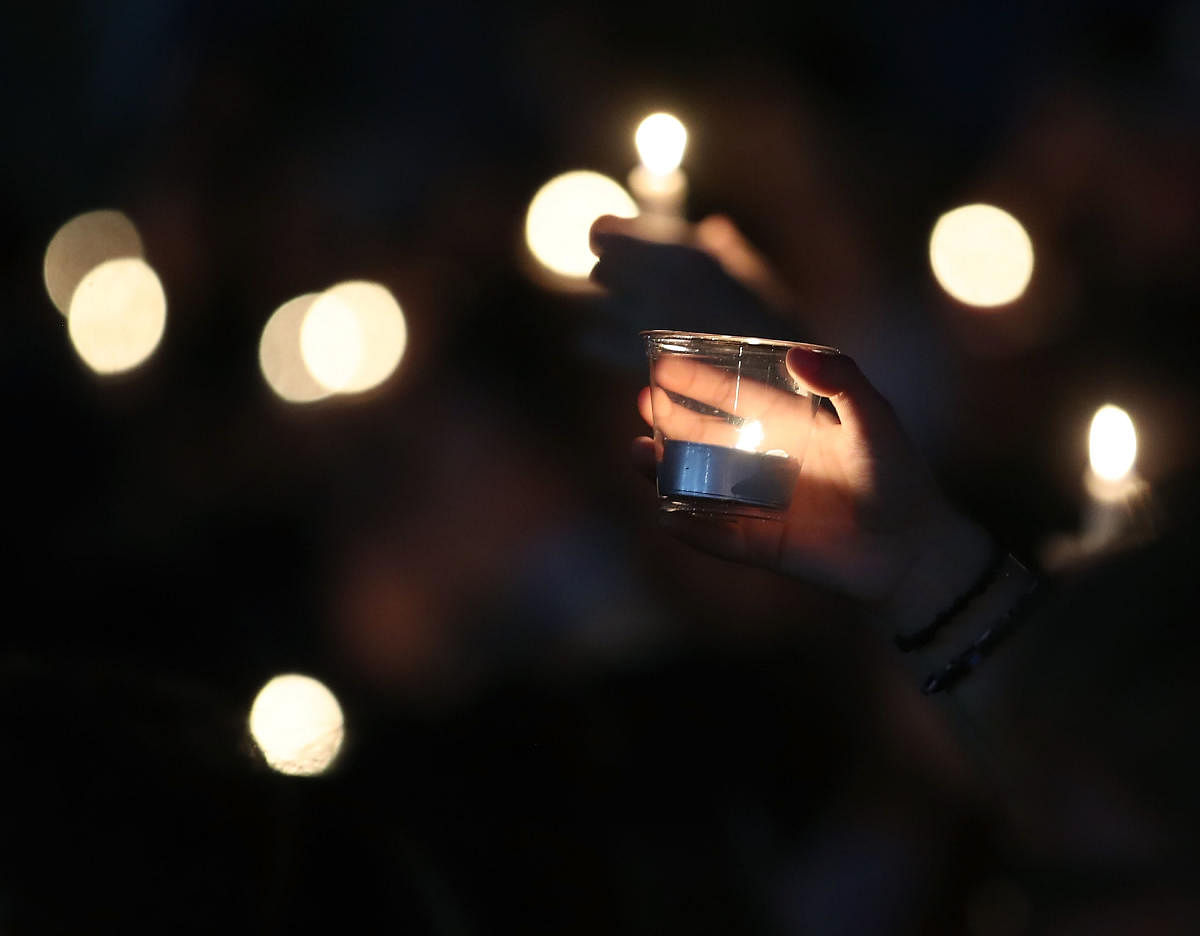 (FILES) In this file photo taken on February 15, 2018, students and family members hold candles during a vigil for victims of the mass shooting at Marjory Stoneman Douglas High School Feburuay 14, 2018, at Pine Trail Park, in Parkland, Florida. - A teenag