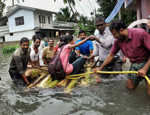 People shift to safe places from a flooded area after heavy rains in Kochi on Monday. PTI Photo
