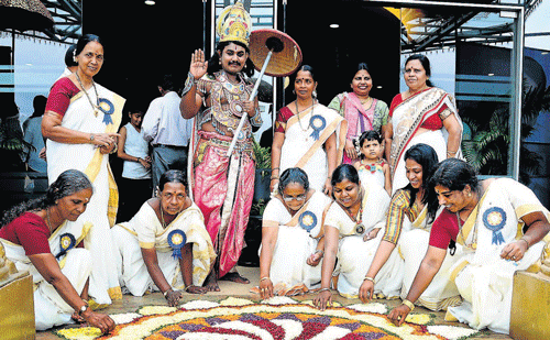 Women from Kerala Samajam busy laying a 'Pookulam' while a man dressed as King Mahabali is all smiles, at Kerala Samajam's Onam celebrations at T M A Pai Hall in Mangalore on Saturday. DH&#8200;Photo
