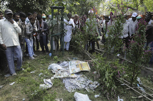 People gather very close to an unexploded bomb, hidden beneath newspapers before it was defused by officials outside the venue of a political rally in Patna, India, Sunday, Oct. 27, 2013. AP