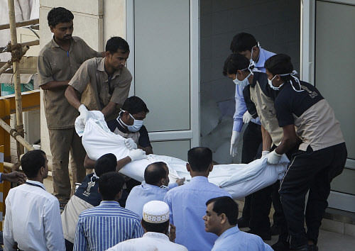 Hospital workers carry the dead body of a victim killed in a stampede outside a morgue in Mumbai January 18, 2014. At least 18 people died in a stampede in Mumbai early on Saturday after thousands gathered to mourn the death of the 102-year-old leader of a Muslim sect, a city official and television reports said. REUTERS