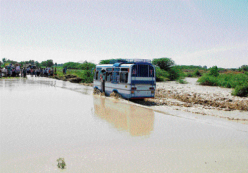 The movement of vehicles was affected at Hiresindogi in Koppal taluk on Wednesday as the road was  submerged in the water from Chennihalla pond. DH photo