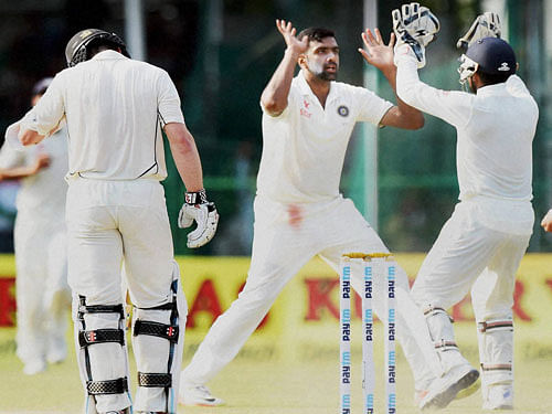 Ravichandran Ashwin with Wriddhiman Saha celebrates the wicket of New Zealand skipper Kane Williamson on the fourth day of the first Test match at Green Park in Kanpur on Sunday. PTI Photo
