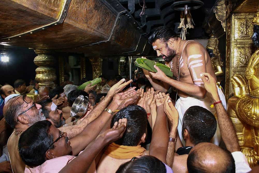 Sabarimala head priest Kandararu Rajeevarau gives 'prasad' to devotee, at Sabarimala temple in Sabarimala. PTI Photo