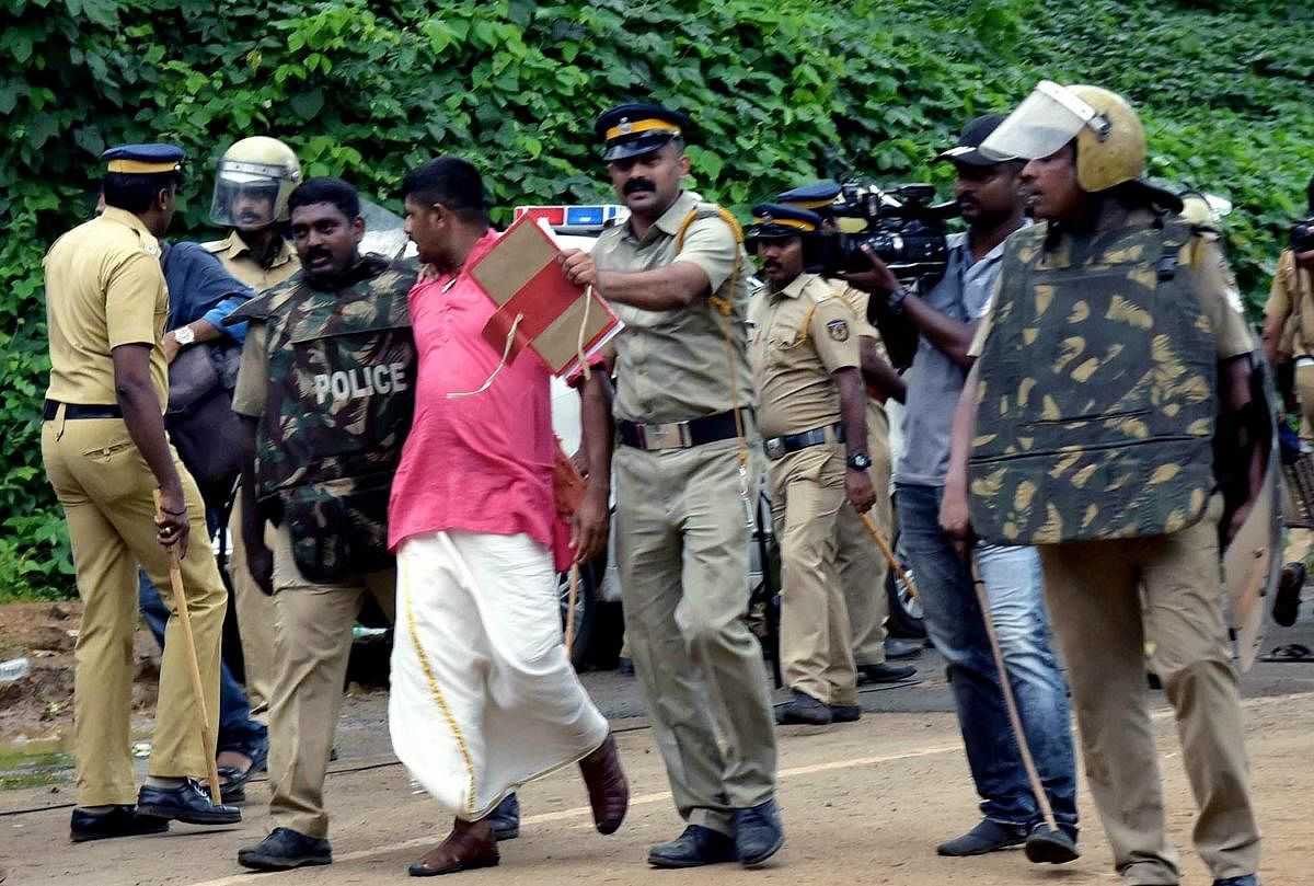 Police take away one of the protesters after they opposed the entry of girls and women of menstrual age into the hill shrine of Lord Ayyappa Temple in Sabarimala, Kerala, Wednesday, Oct 17, 2018. Tension was witnessed outside the temple on its opening day. PTI