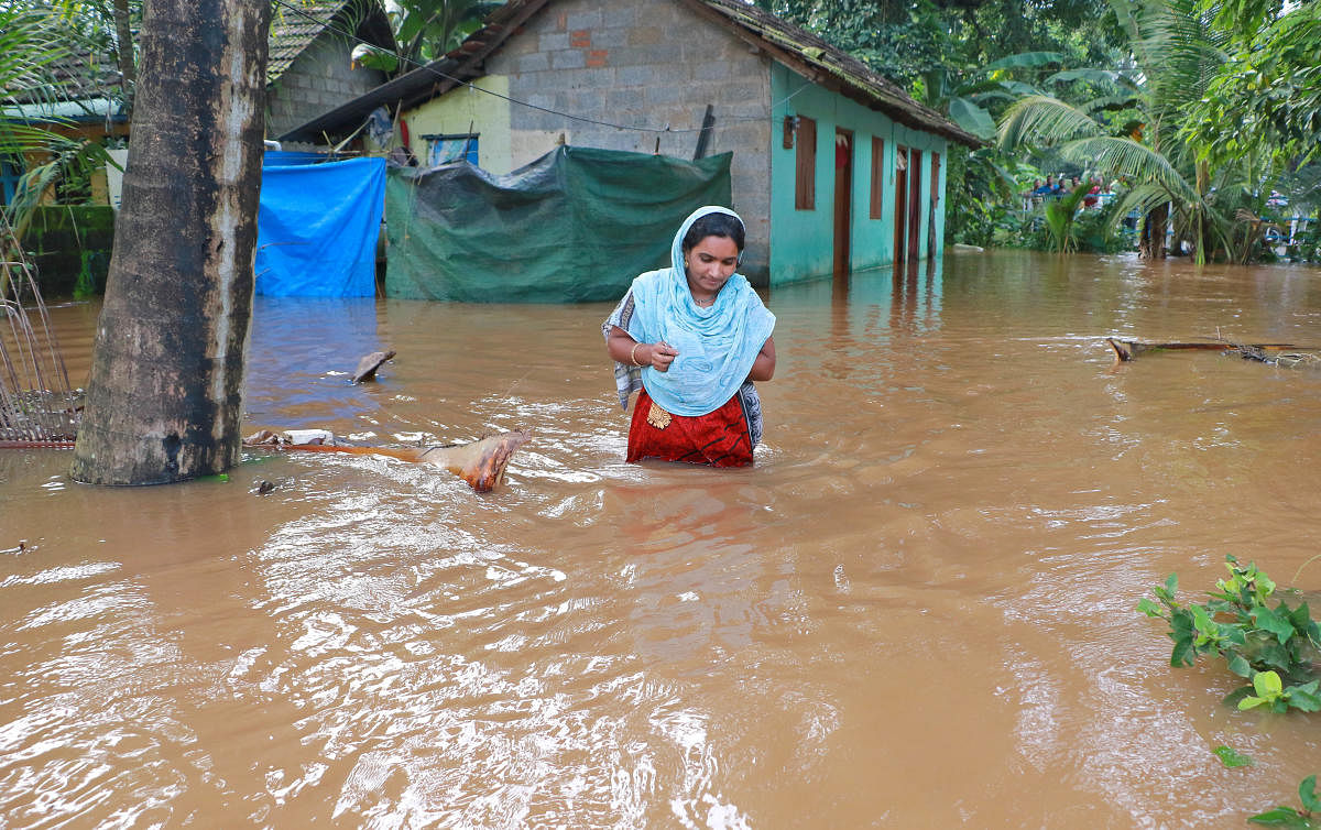 A woman wades through flood water in Eloor in Ernakulam district. DH Photo