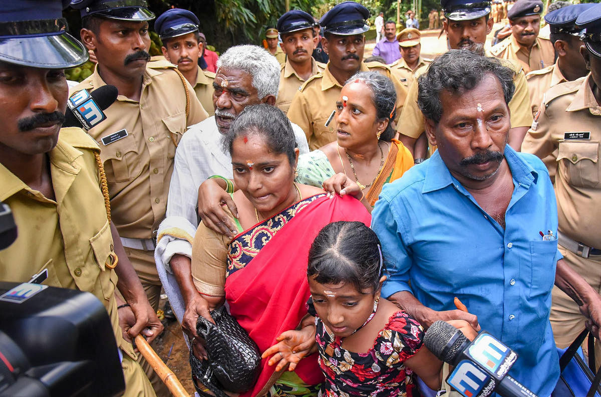 Police escort Madhavi and her family members after she was heckled by protesters while seeking entry to the Ayyappa Temple on Wednesday. PTI