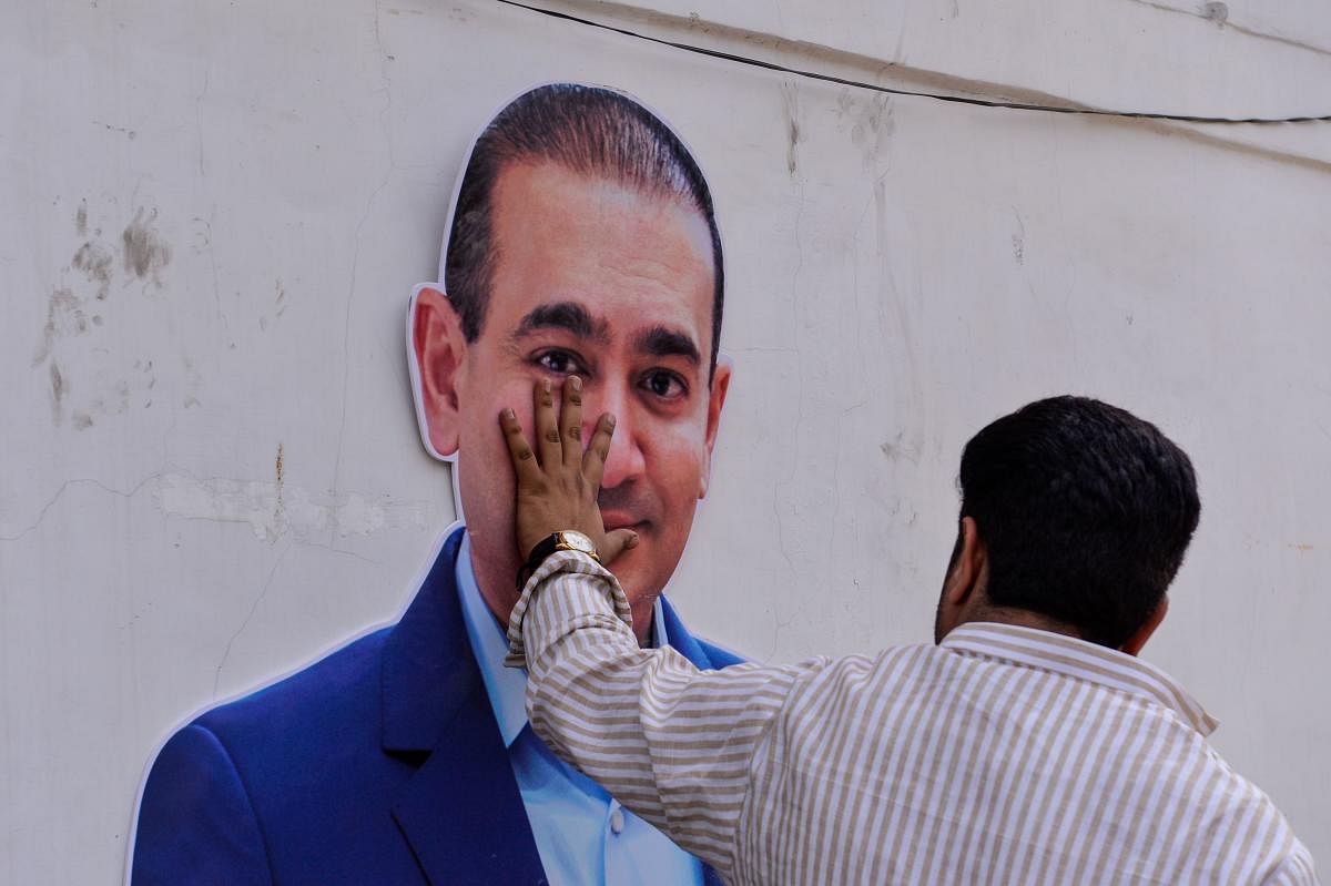 A man keeps his hand on a cut-out of billionaire jeweller and loan defaulter Nirav Modi in New Delhi on February 16, 2018. AFP
