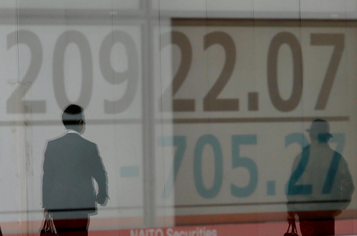 Men are reflected on an electronic board showing the Nikkei stock index outside a brokerage in Tokyo. Reuters