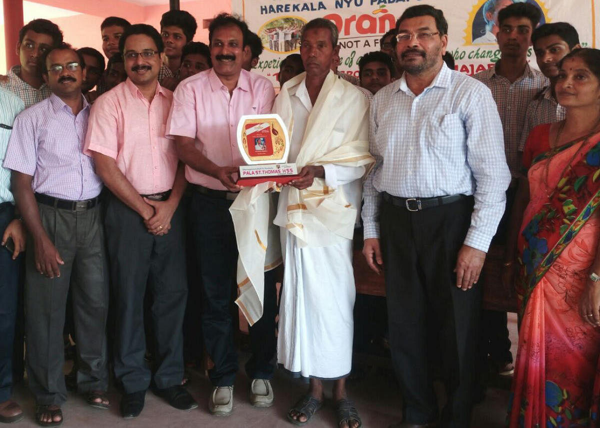 St Thomas High School (Kottayam) Principal Mathew M Kuriakose felicitates Harekala Hajabba at Govt school in Harekala on the outskirts of Mangaluru on Wednesday. Karnataka Janapada University former VC Prof Chinnappa Gowda among others look on.