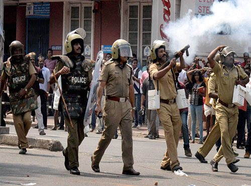 Policeman lobbing tear gas shell to disperse CPI(M) activists during clashes at Palayam in Thiruvananthapuram. PTI Photo