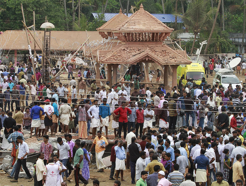 People walk past debris after a fire broke out at a temple in Kollam. Reuters photo