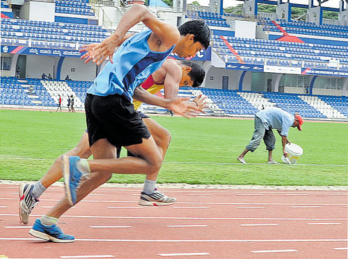 final touches Delhi's Beant Singh (left) during a warm-up session. Athletes train as the ground staff is busy preparing the pitch for the football tie at the Sree Kanteerava  stadium in Bengaluru on Monday. DH photo