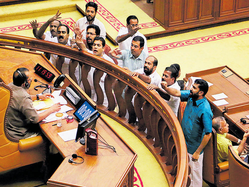 Congress-led Opposition legislators shout slogans in front of  Speaker P Sreeramakrishnan's chair in the Assembly in  Thiruvananthapuram on Friday. PTI