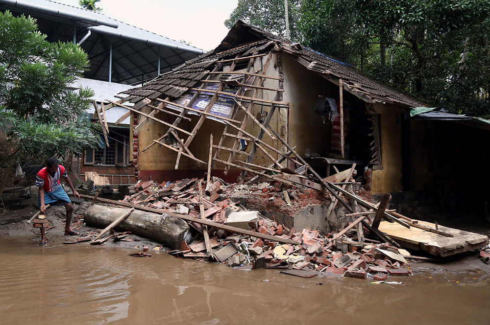 A man removes debris from a collapsed house after floods in Paravur, Kerala. Reuters Photo