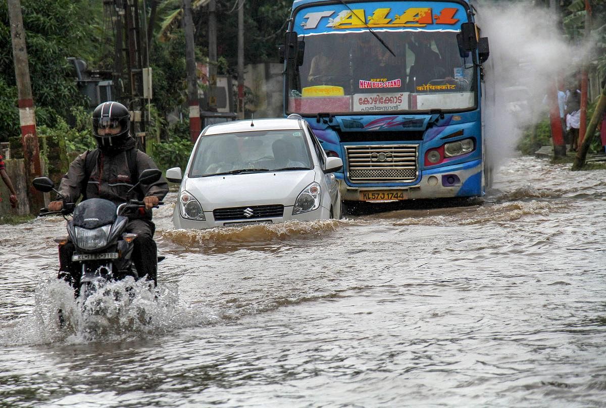 Commuters wade across a waterlogged road following monsoon rainfall at Vengeri in Kozhikode. PTI file photo.
