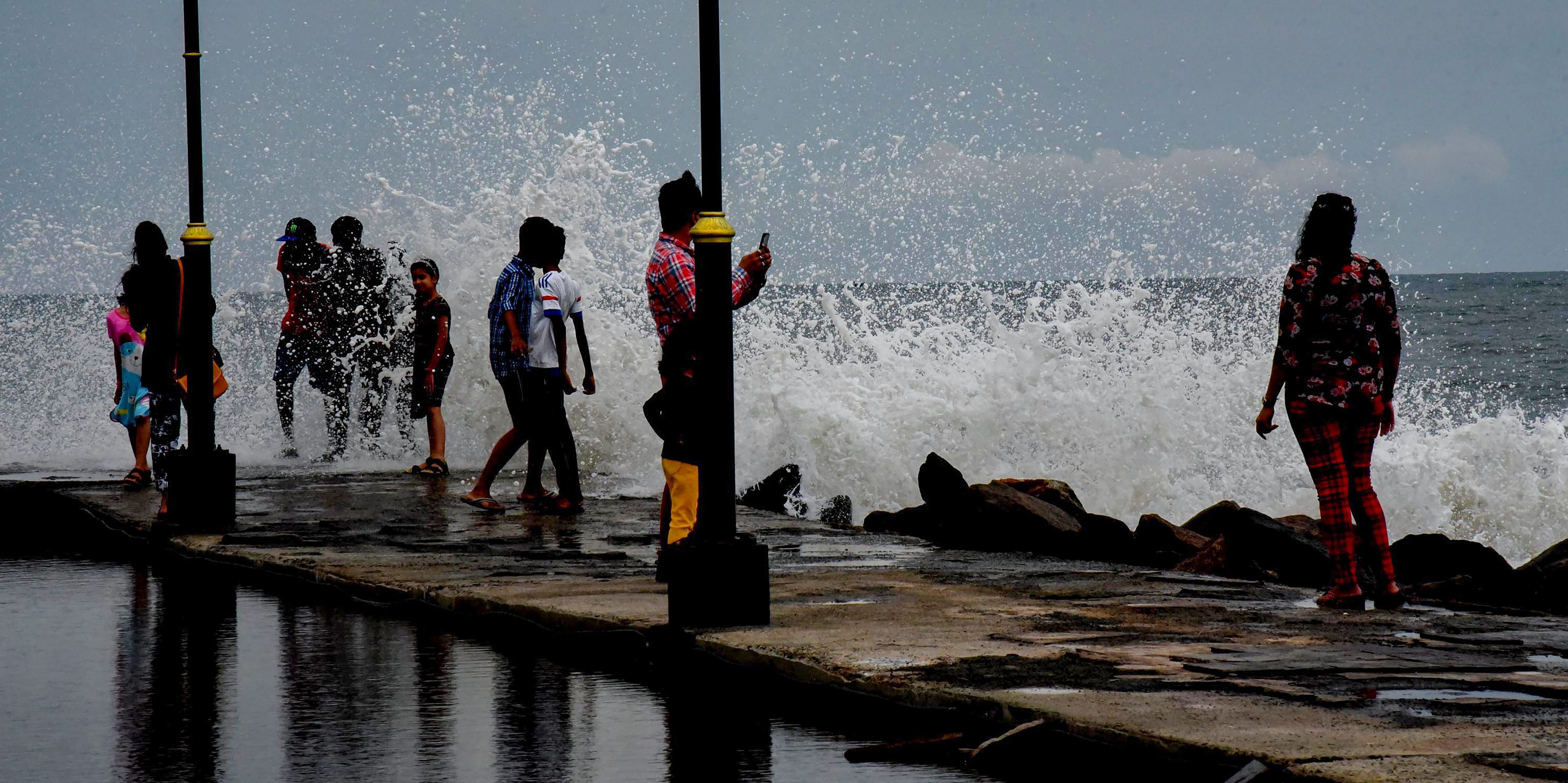 People react as a big wave hits the seawall during sunset, in Kochi, Kerala, on Wednesday. According to the Meteorological Department, the southwest monsoon hit Kerala, three days before its scheduled arrival. PTI 