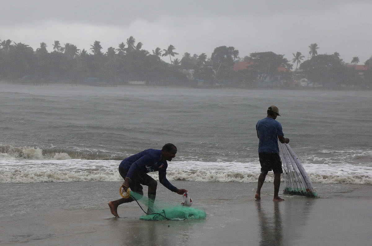 Fishermen prepare to cast their nets during a sudden downpour at the Fort Kochi beach in Kerala. PTI