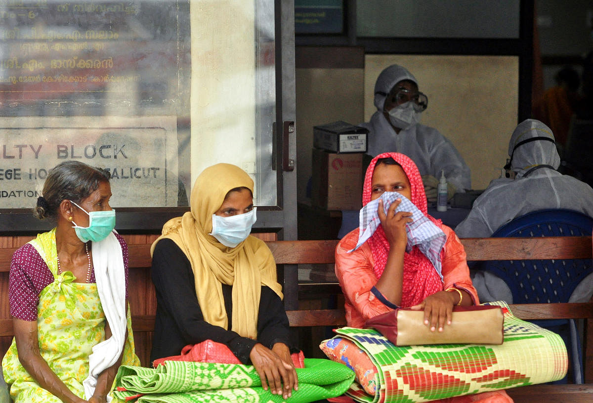 People wear masks as they wait outside a casualty ward at a hospital in Kozhikode. Reuters Photo