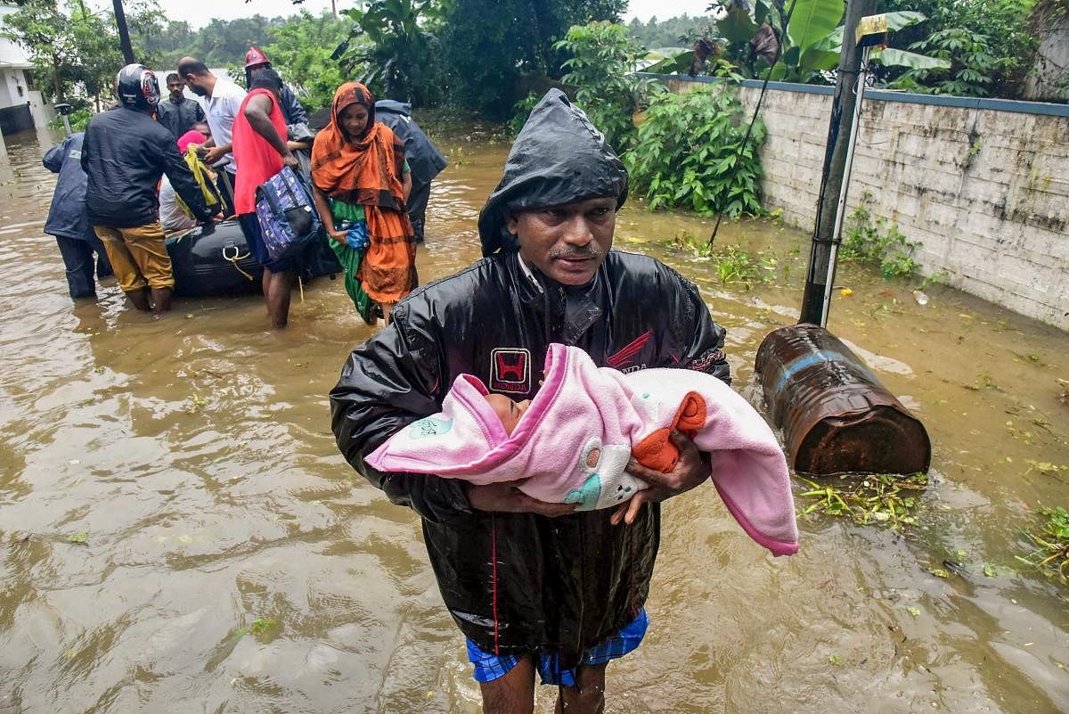 A rescuer carries an infant as people are evacuated from a flood-hit locality in Kochi on Wednesday, Aug 15, 2018. The Cochin International Airport at Nedumbassery reportedly suspended operations till Saturday due to rains and floods. PTI Photo