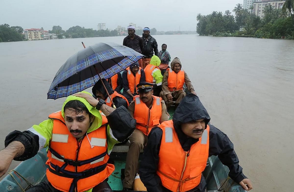 Indian fire and rescue personnel evacuate local residents in a boat following monsoon rains at Aluva, Kerala, on Thursday. AFP