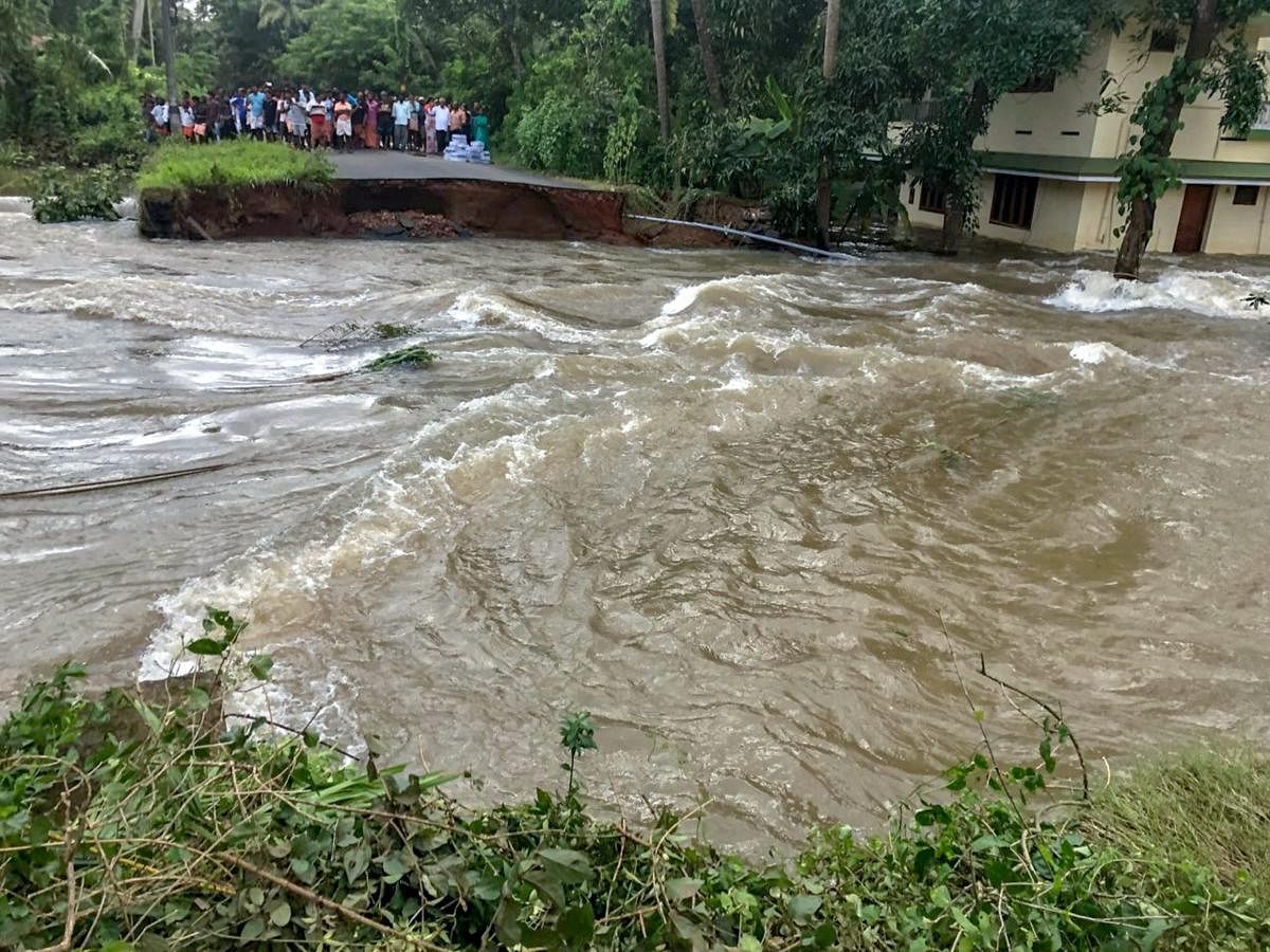 People marooned at a damaged road in a flood-hit area in Thrissur district in Kerala on Monday. Coast Guard Photo via PTI