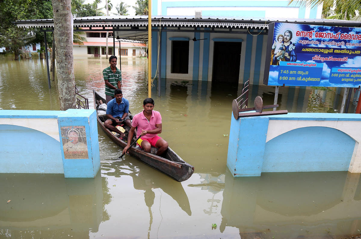 Men paddle their boat through the lawns of a partially submerged church at Kuttanad in Alleppey district, Kerala. Reuters Photo