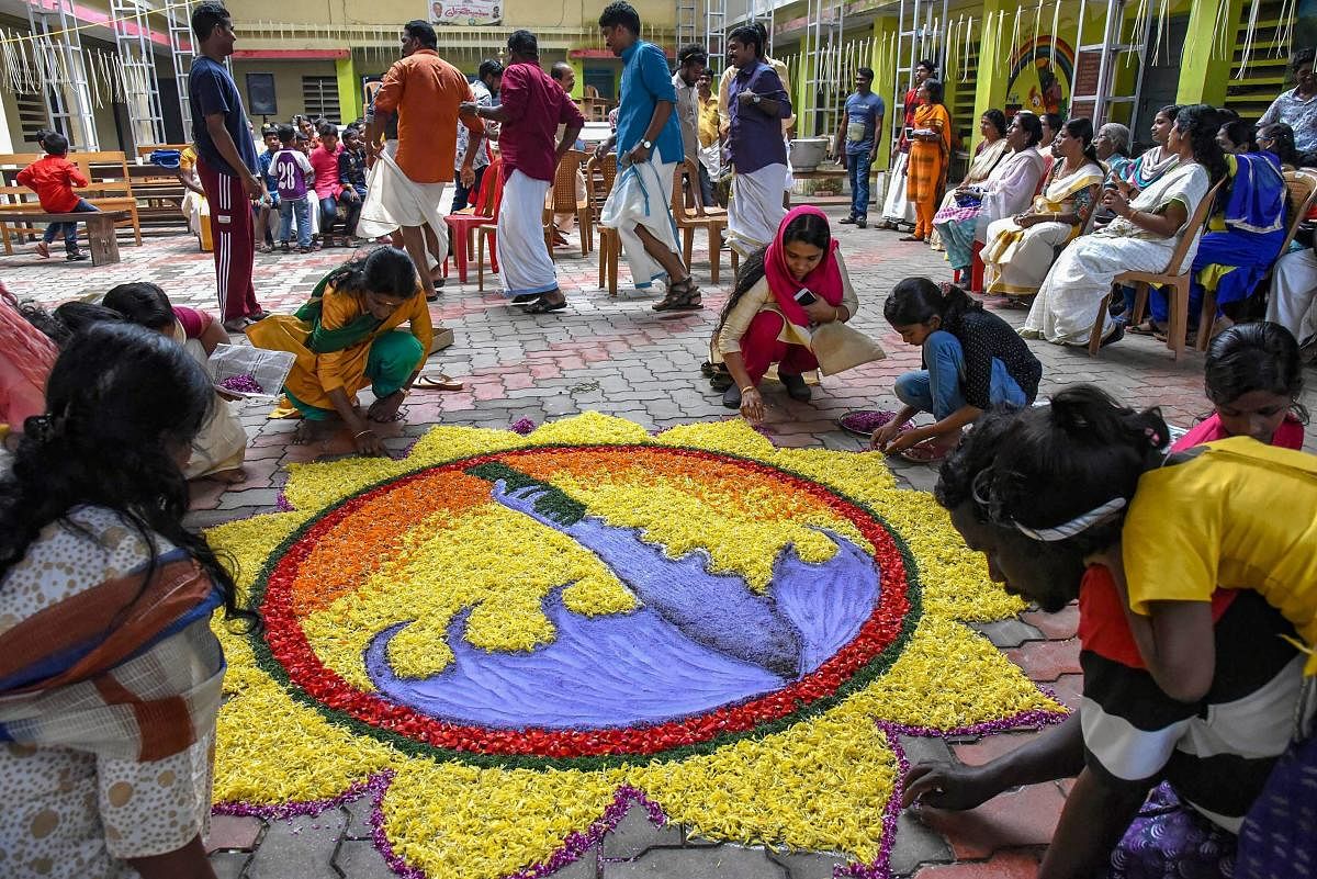 Women make a rangoli as they celebrate Onam at a flood relief camp in Kochi. PTI file photo