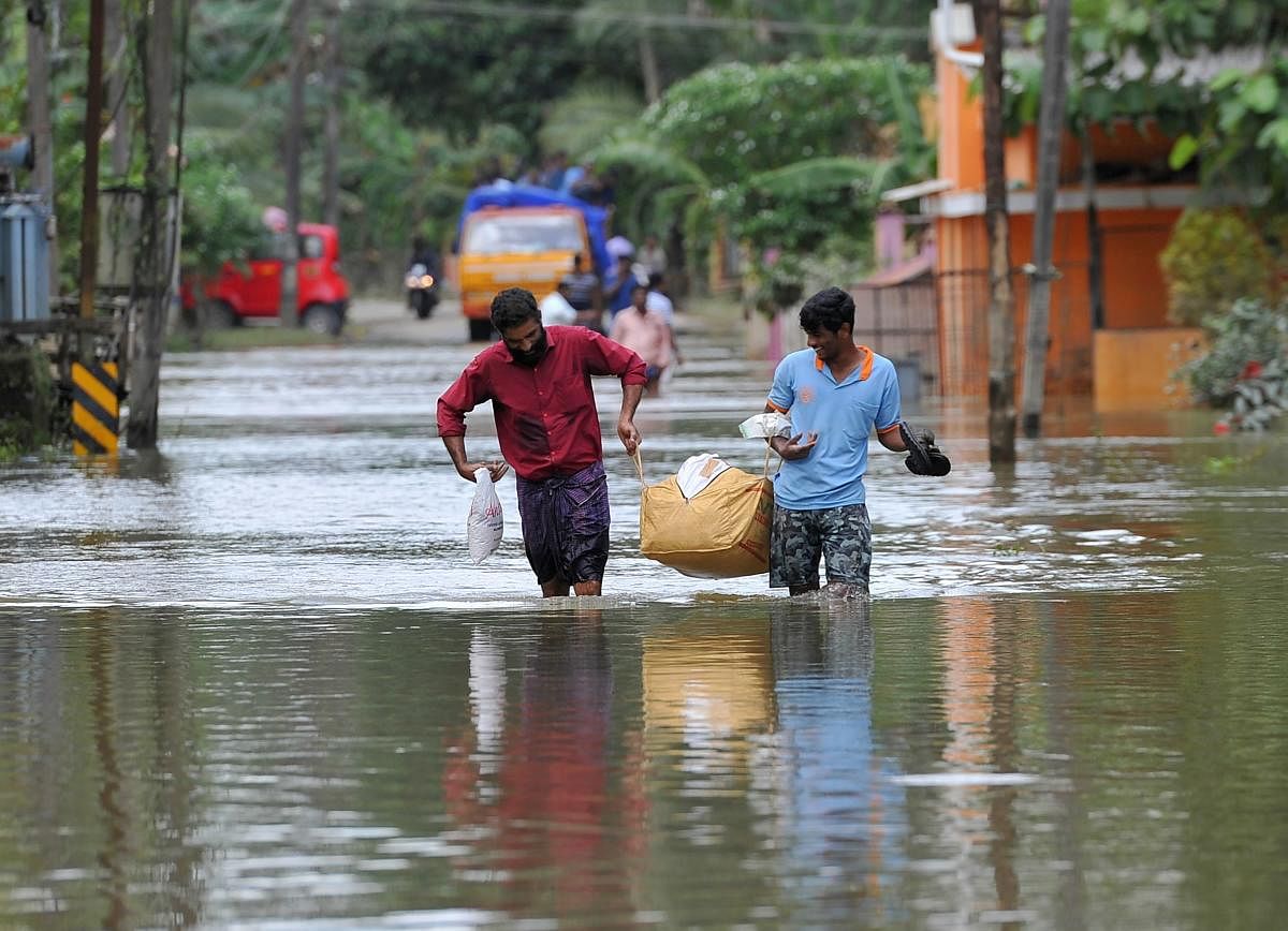 Men carry food and water distributed to people stranded by floods at Pandanad in the Alappuzha district of Kerala. (AFP File Pic)