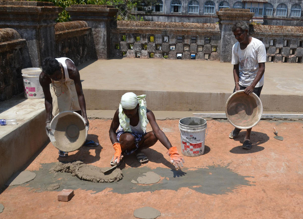 Workers cover the damaged part of Madikeri Old Fort with concrete mixture.