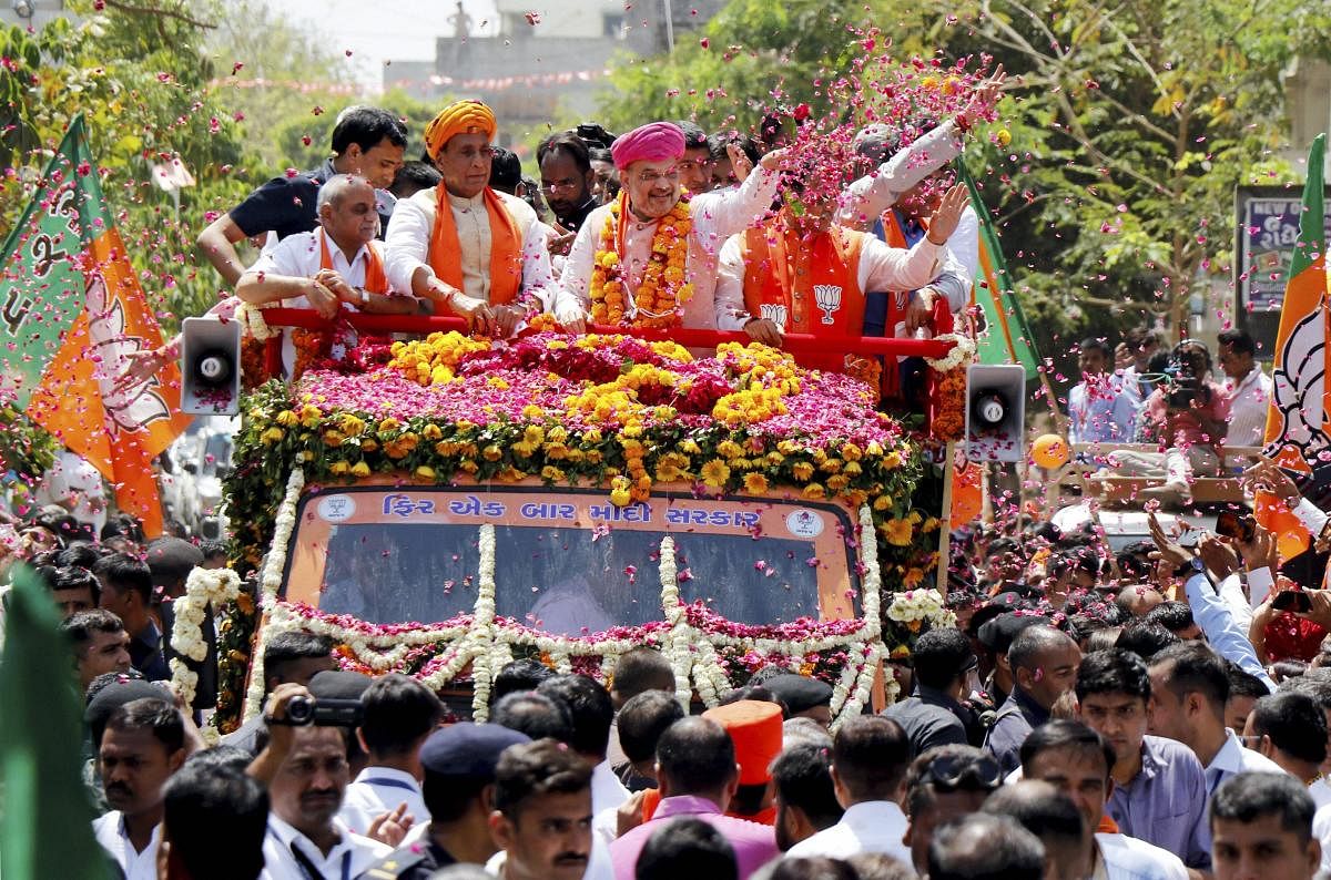 BJP National President Amit Shah waves to his party supporters as Home Minister Rajnath Singh and other leaders look on during a roadshow ahead of the former's nomination filing from Gandhinagar constituency for the upcoming Lok Sabha elections, in Ahmedabad. (PTI Photo)