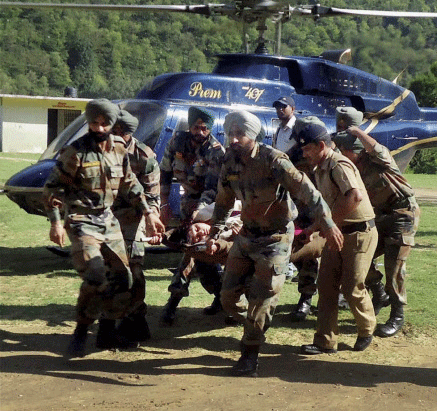 Army personnel carry an injured flood victim on a stretcher for treatment at Hemkund in Uttarakhand on Wednesday. PTI Photo.