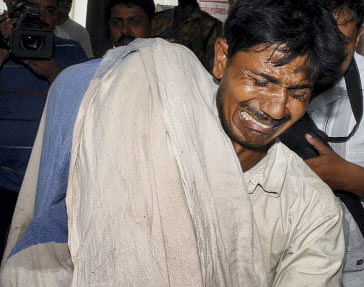 A man mourns as he holds his dead daughter in Patna Medical College & Hospital after at least 20 children died and many more were sick after eating lunch at a primary school in Chapra, in Patna on Wednesday. PTI photo