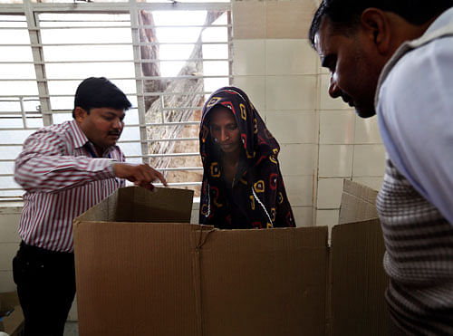 Election officials help a woman cast her vote in New Delhi on Wednesday, Dec. 4, 2013. AP Photo