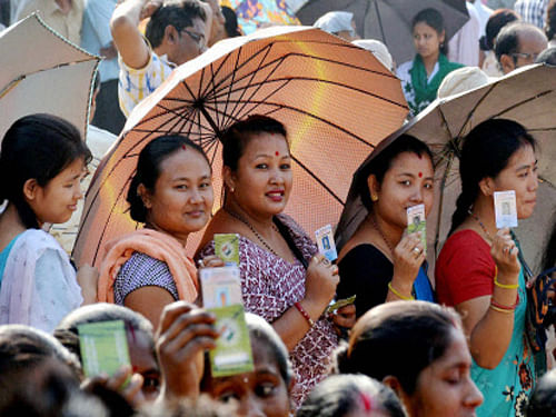 Woman voters show their voter identity cards as they wait in a queue to cast votes for Lok Sabha polls outside a polling station, in Guwahati on Thursday. PTI Photo