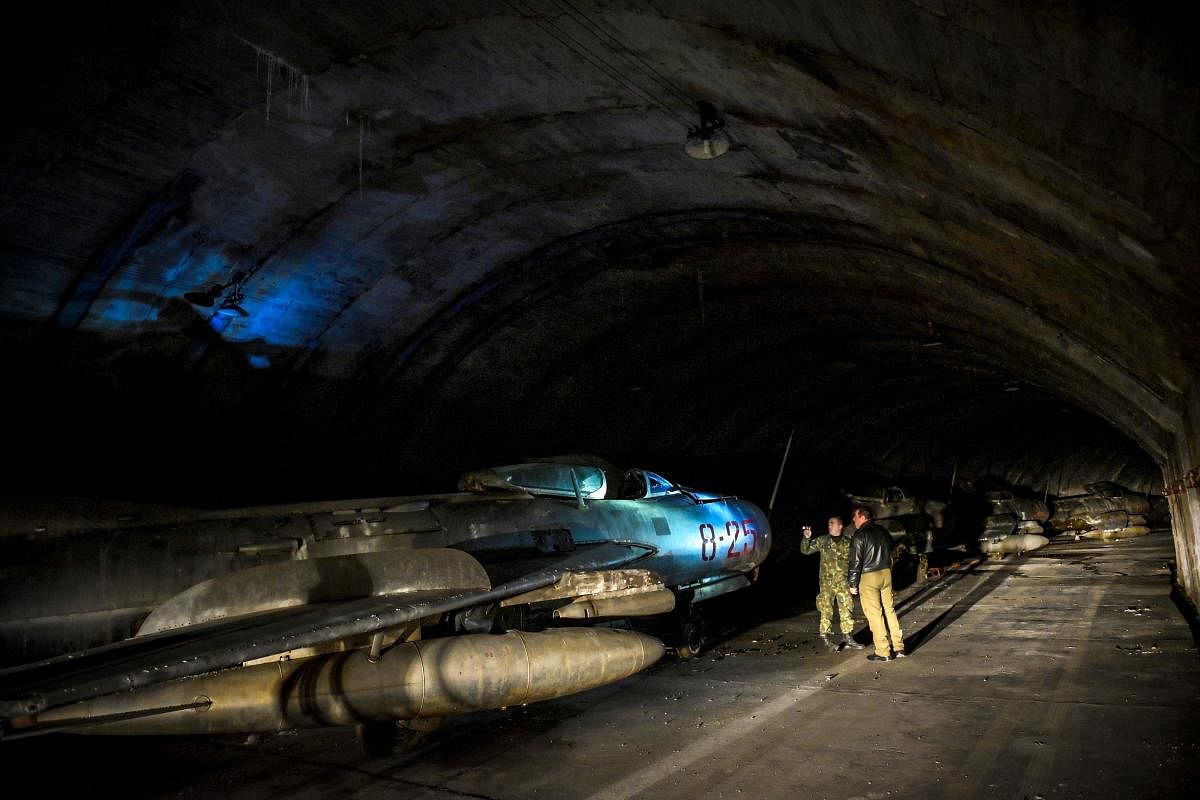 Albanian military personnel walk next to MIG-19 jet fighters inside the main tunnel of the Gjader Air Base built near the city of Lezhe. (AFP Photo)