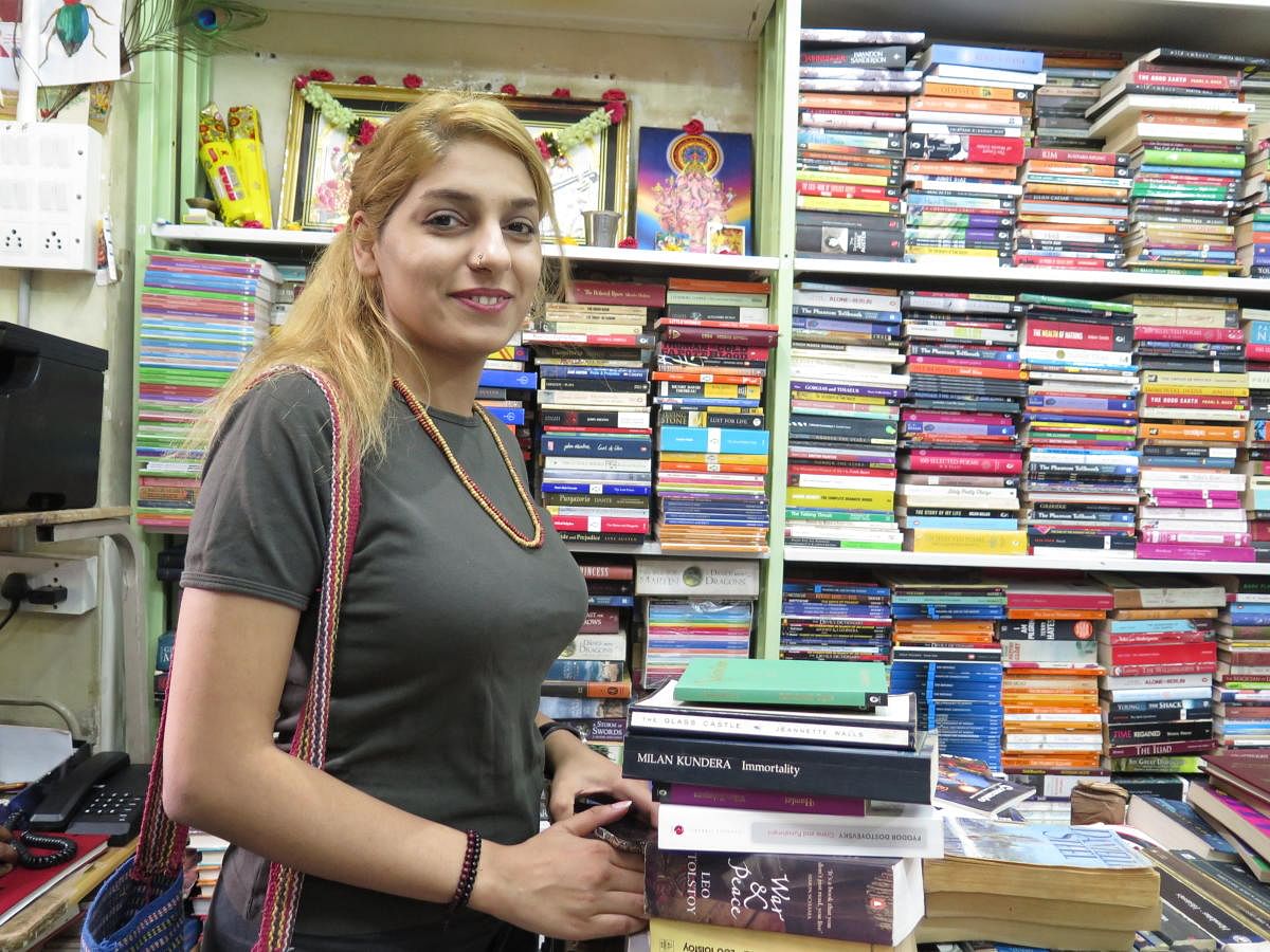 Mina G.H. from Iran, stands next to a stack of books she plans to purchase at a bookstore in Bengaluru on April 2, 2019.