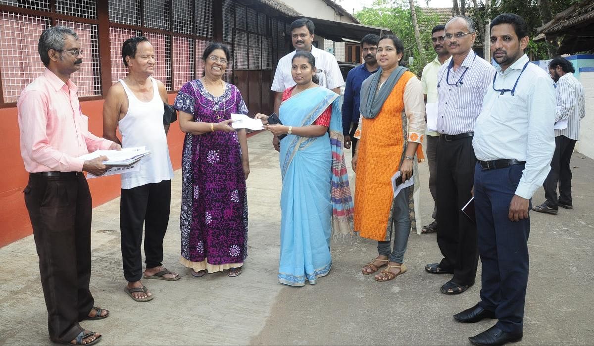 Deputy Commissioner Hephsiba Rani Korlapati hands over a voter slip to a voter in Udupi.