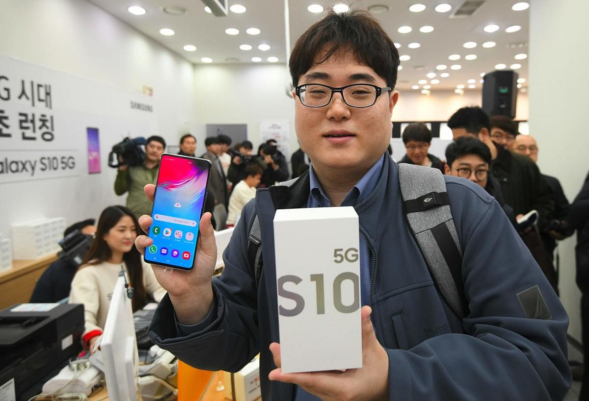 The day's first SK Telecom 5G customer shows his new Samsung Galaxy S10 5G smartphone during a launch event at an SK Telecom shop in Seoul on April 5, 2019. - The world's biggest smartphone and memory chip maker Samsung Electronics warned of a 60 percent-