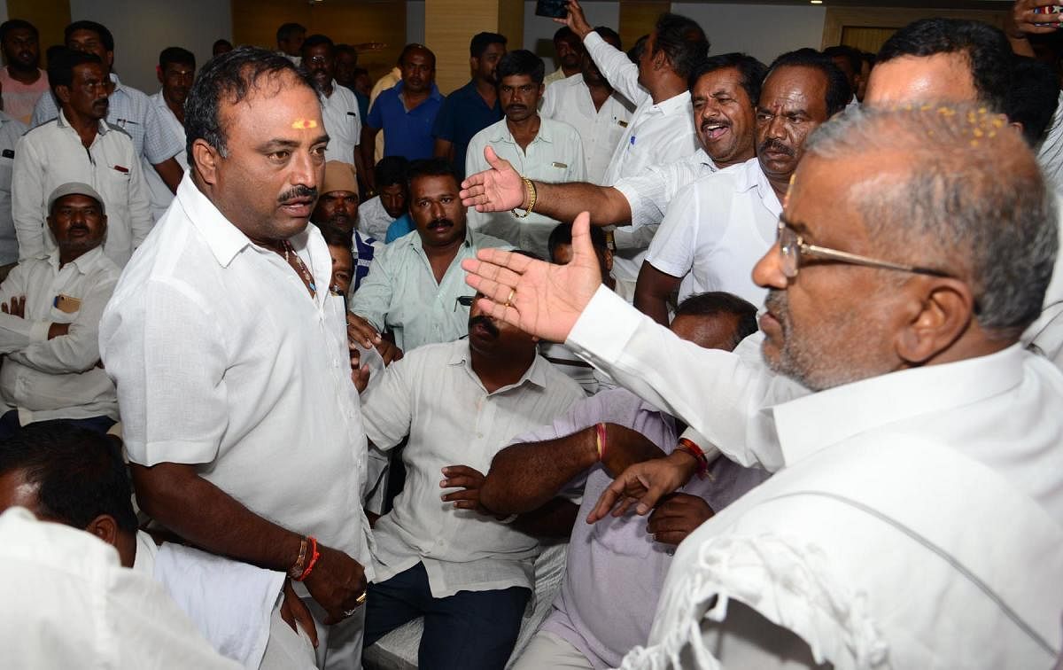 Minister G T Devegowda (right) tries to pacify JD(S) workers at a party meet in Mysuru on Friday. DH photo/Nesara Kadanakuppe
