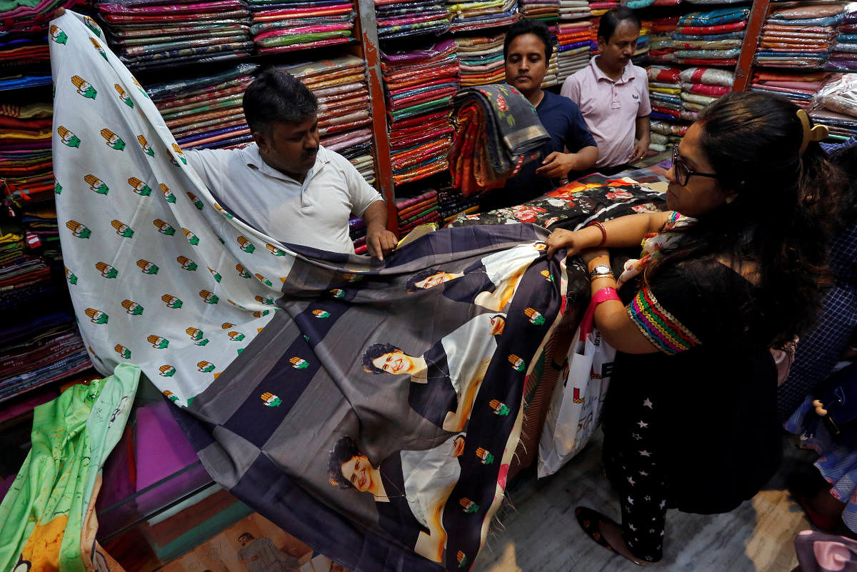 A salesman shows a sari with printed images of Priyanka Gandhi Vadra to a customer inside a shop in Kolkata. PTI file photo