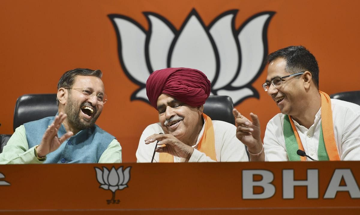 Union Minister and BJP leader Prakash Javadekar share a light moment with Gurjar leader Kirori Singh Bainsla and his son Vijay Bainsla during a press conference after they joined BJP, ahead of Lok Sabha polls in New Delhi on Wednesday. PTI photo