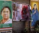 Trinamool Congress workers paste posters of former Prime Minister the late Indira Gandhi and party chief Mamata Banerjee at a building ahead of the assembly polls in West Bengal, in Kolkata on Wednesday. PTI Photo