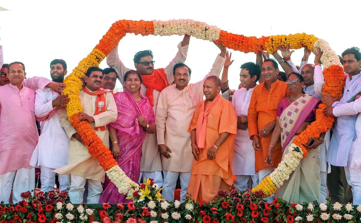 Dadri : Uttar Pradesh Chief Minister Yogi Adityanath being garlanded at an election rally in support of Union Minister and BJP candidate Mahesh Sharma, ahead of the Lok Sabha elections, in Dadri, Sunday, March 31, 2019. (PTI Photo)