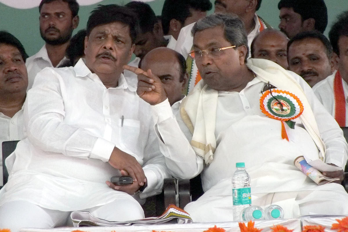 Former minister Dr H C Mahadevappa and former chief minister Siddaramaiah share a word during the Congress Parivarthana rally, in Chamarajanagar, on Friday.