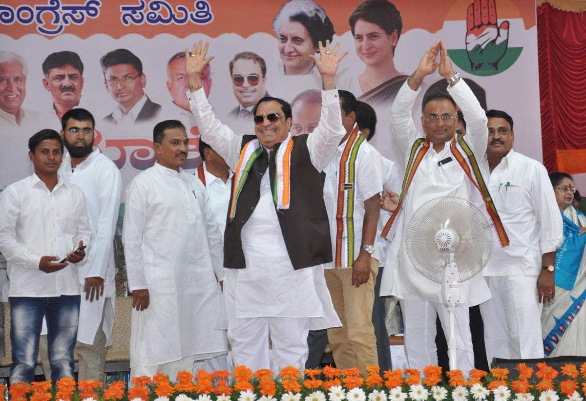 Congress leader C M Ibrahim and KPCC president Dinesh Gundu Rao wave at the people during Parivartana rally, at Dr B R Ambedkar Stadium in Chamarajanagar on Friday. dh photo