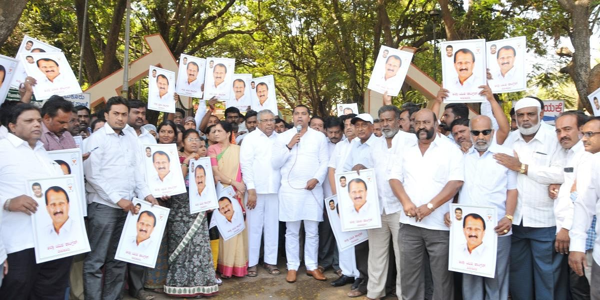 The office-bearers of Tumakuru District Congress Committee and the party workers stage a protest holding pictures of MP S P Muddahanumegowda in Tumakuru on Saturday. DH PHOTO